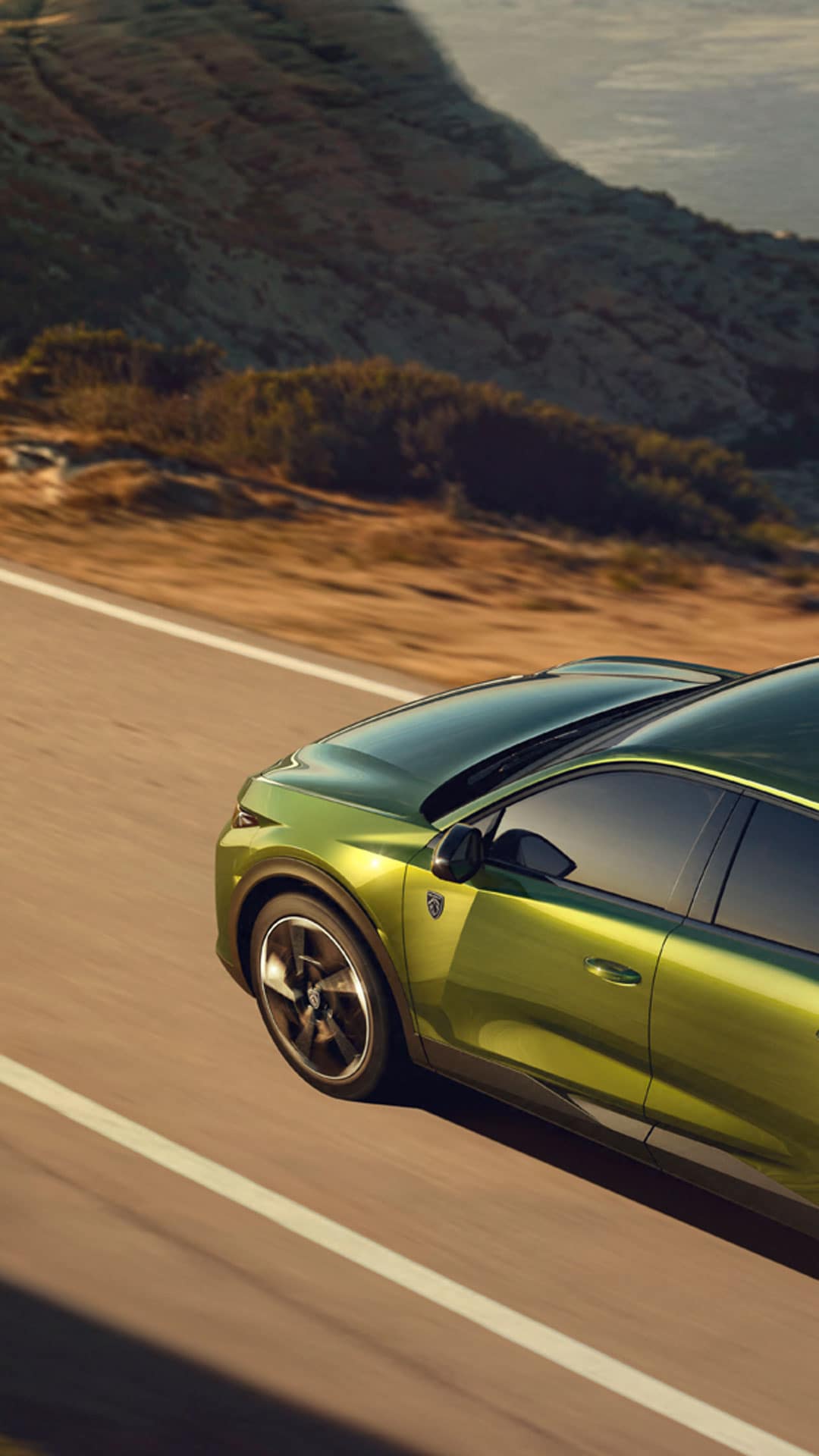 Nouvelle PEUGEOT E-408 roulant sur une route de bord de mer